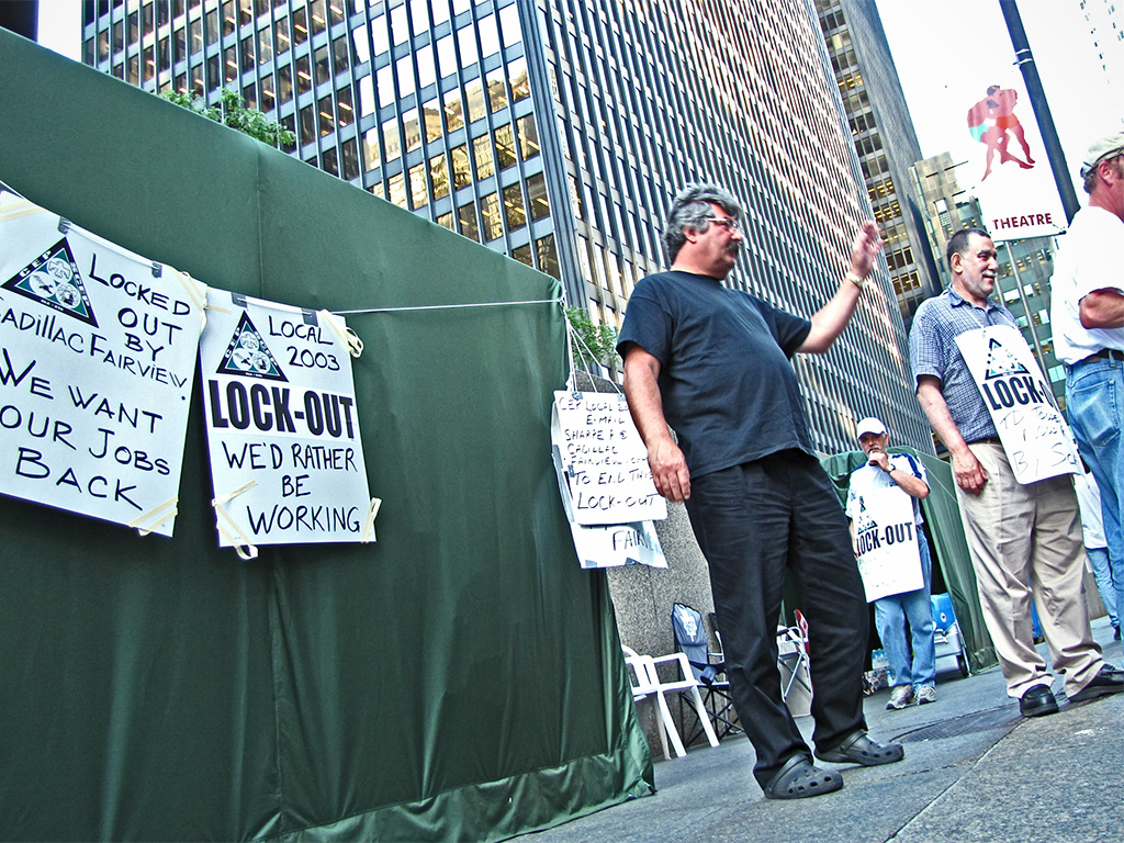 a man standing on a sidewalk near a protest wall