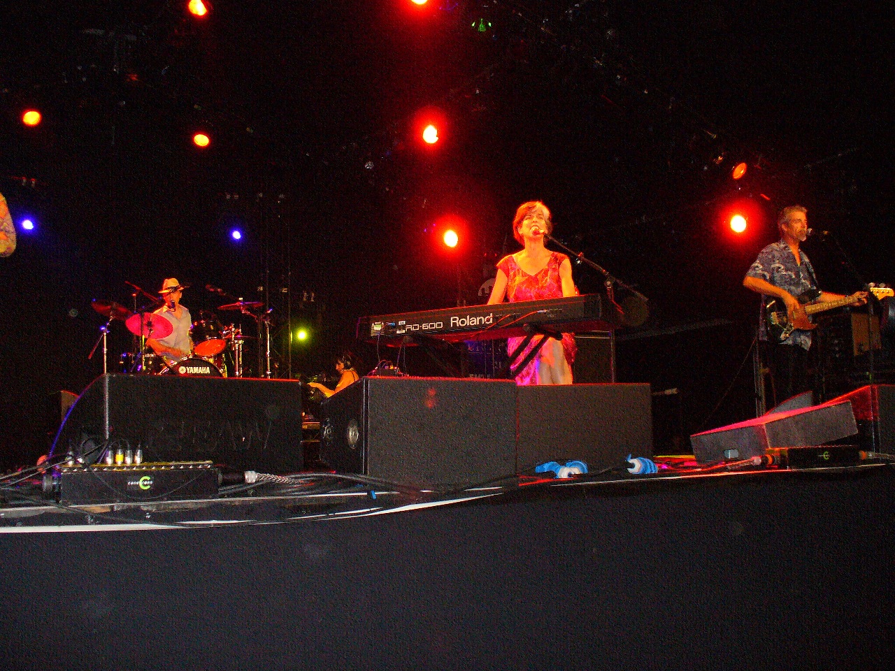 three people playing on keyboards and piano in front of colorful lighting