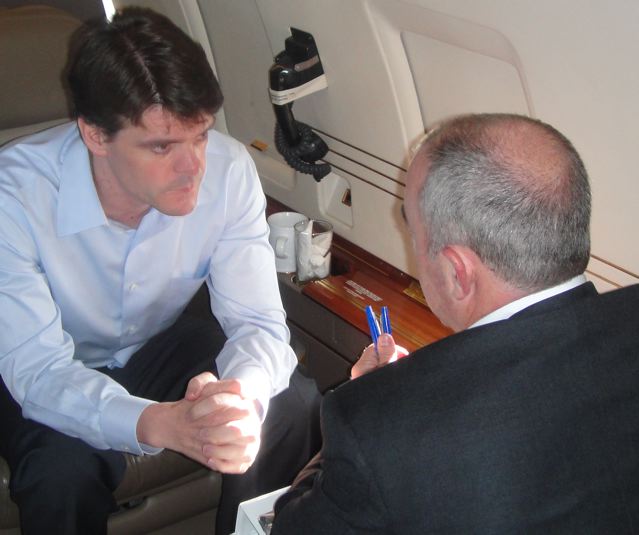 a man sitting on an airplane looking at soing in his hand