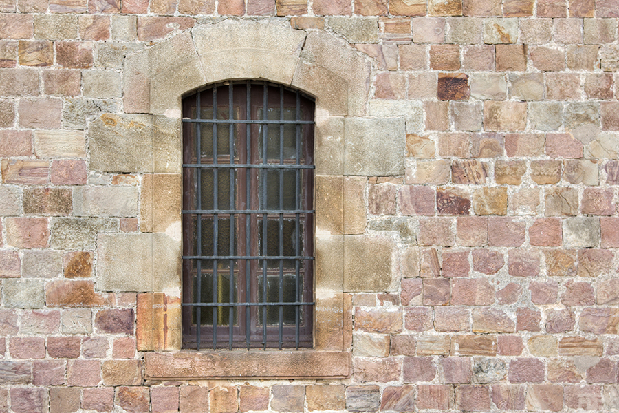a barred window on a stone wall with bars on it