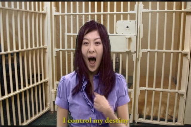 an idiot appears to be making an odd face as she stands inside a cell with several bars behind her