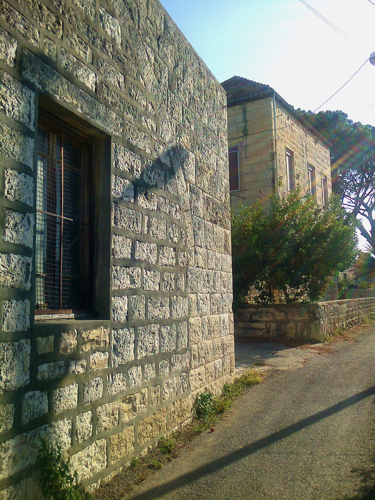 a brown brick building with a window and a stone wall