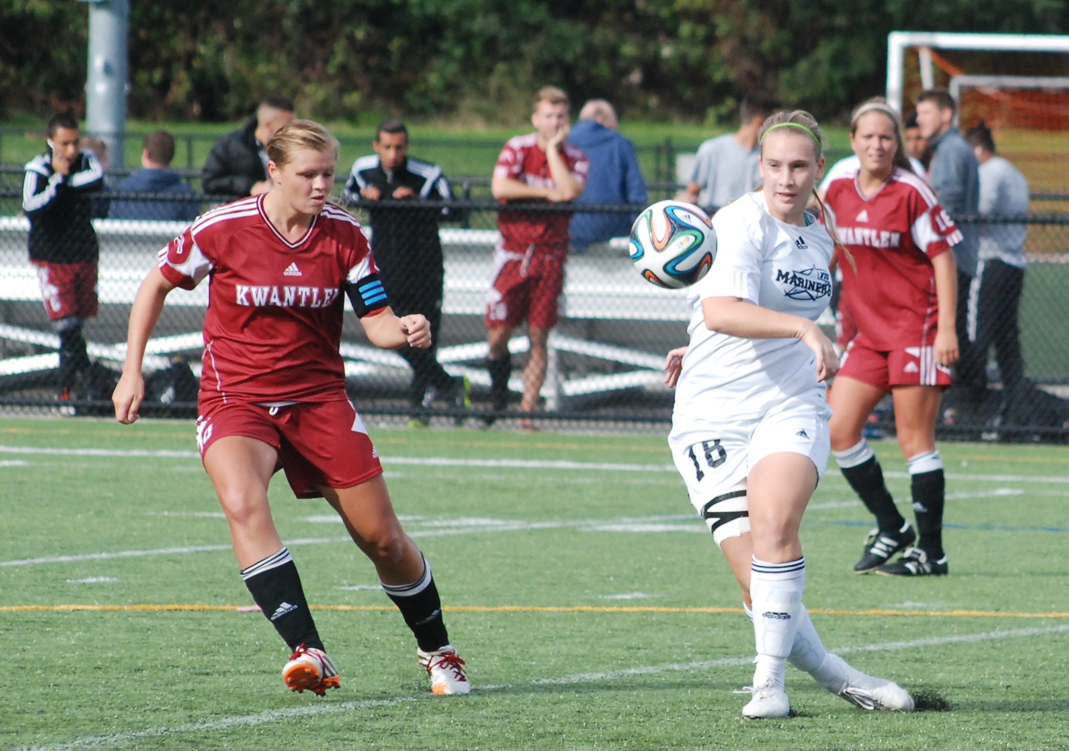 two female soccer players playing soccer while crowd watches