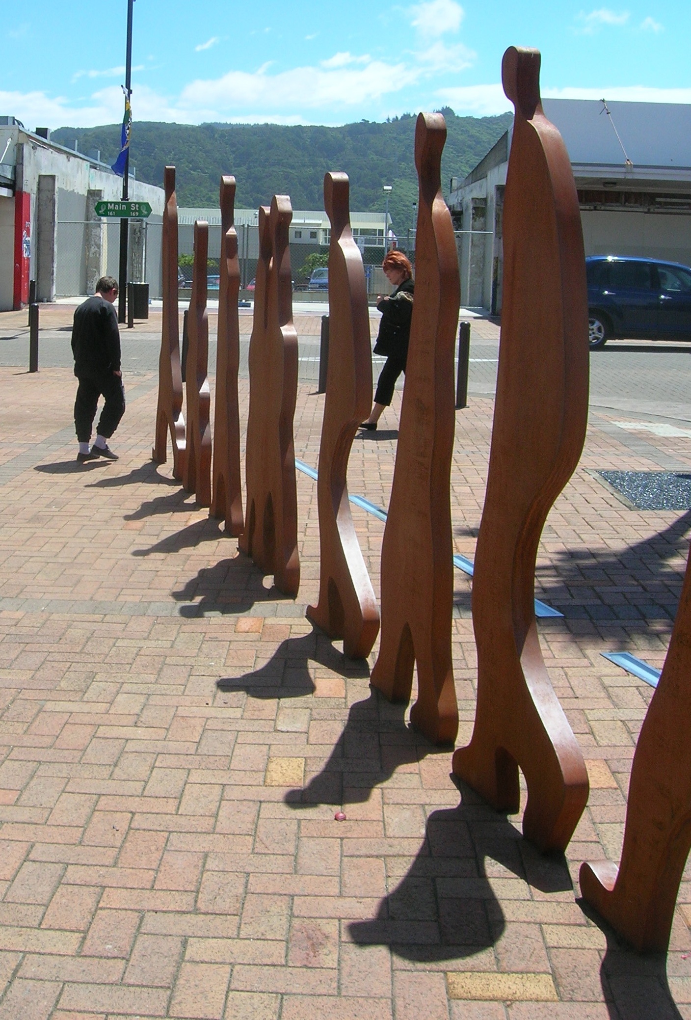 a line of wooden statues sitting on top of a brick walkway