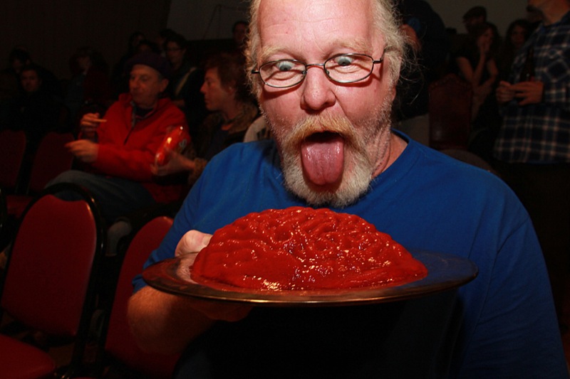 man making a funny face with a deep - cooked food item on a plate
