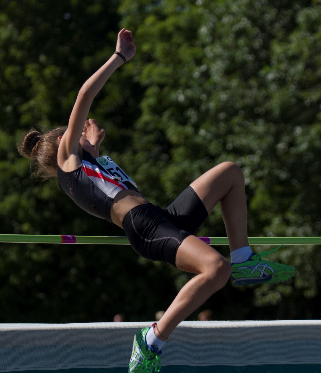 a woman jumps while playing tennis on a court