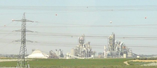 a building and power lines in the distance with an industrial park on the side