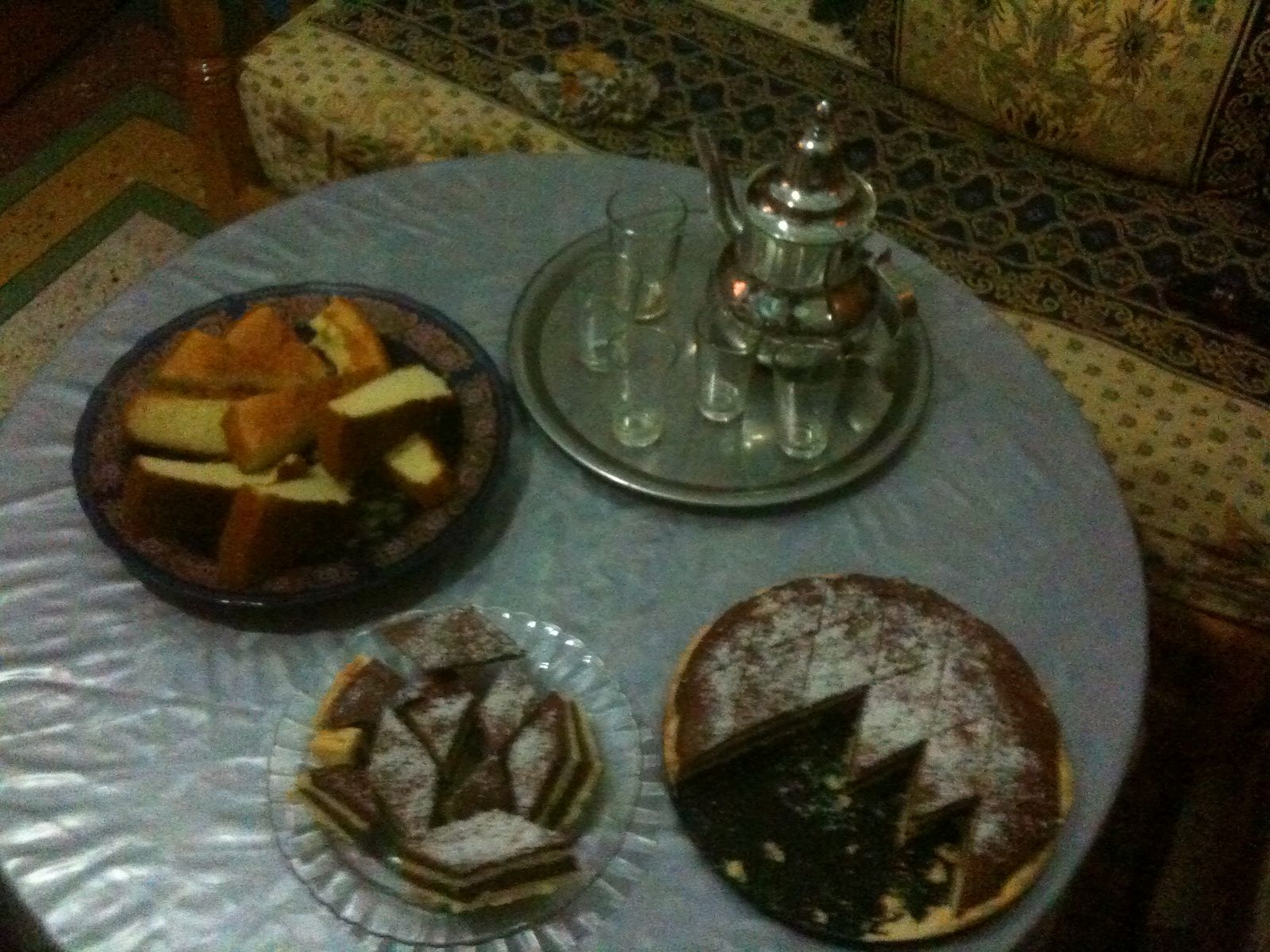 two small plates of pastries with silverware sit on a table next to a tea kettle