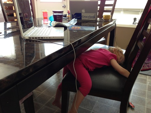 a young woman with her head under a desk