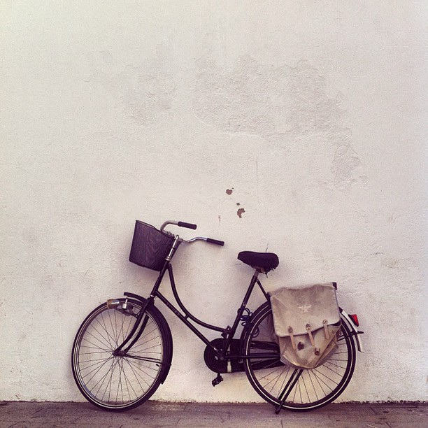 a bike leaning against a white wall with an item in the basket