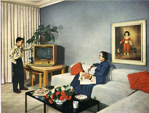 man standing behind a man sitting in front of a television