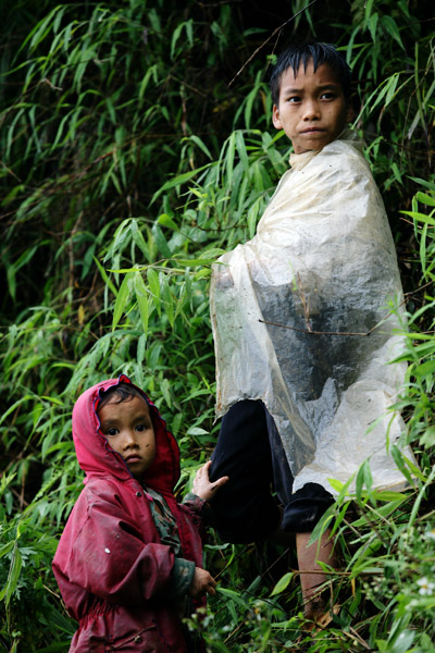 a boy is holding a cover while standing next to a woman in a bush
