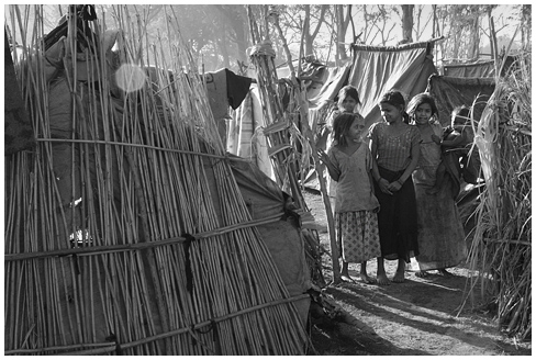 two women standing next to each other near some native grass huts