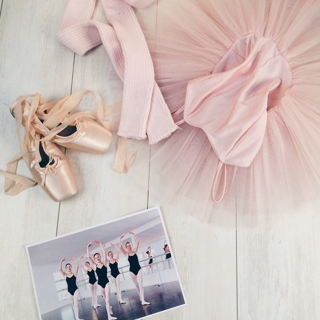 a pair of ballet shoes, a tutu and a skirt on a white wooden floor