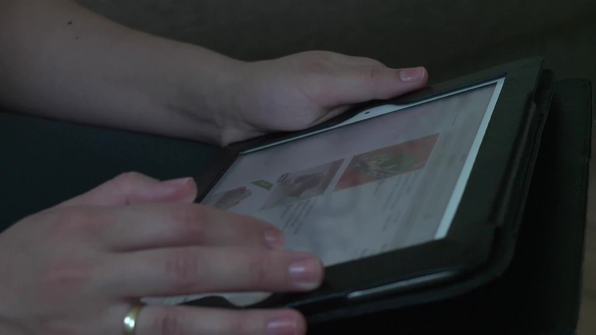 hands are holding and operating the screen of a tablet