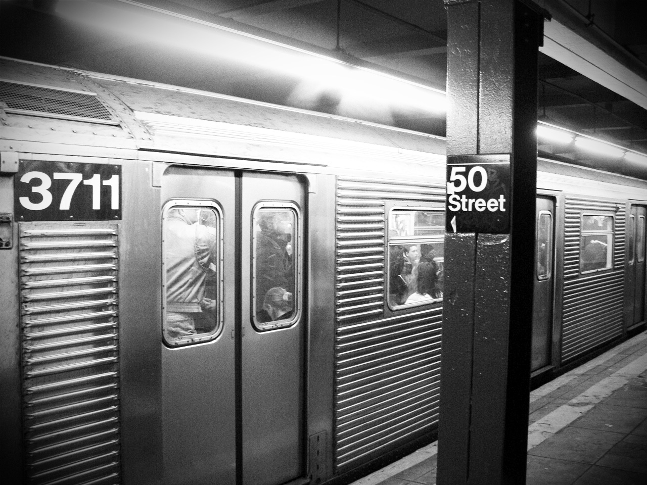 a subway train sits at the station, where a sign is on