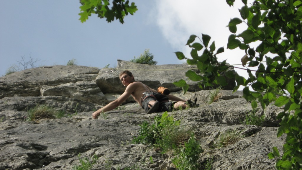 a shirtless man sitting on top of a rock covered mountain