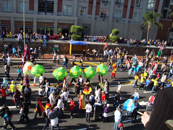 large group of people walking down street carrying balloons
