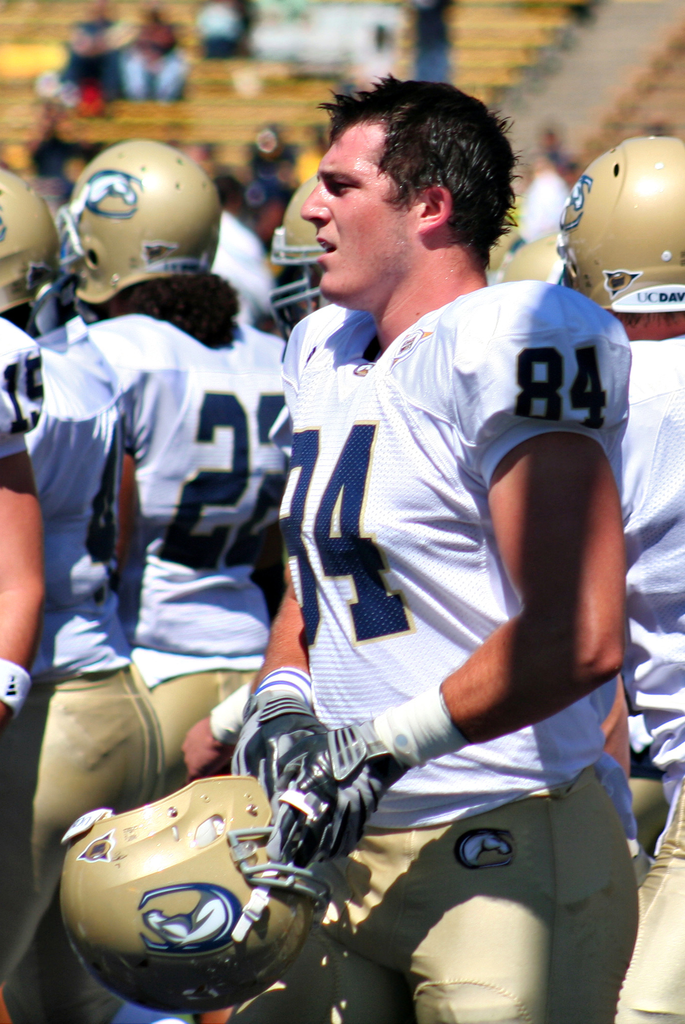 a football player wearing a white uniform with a tan helmet