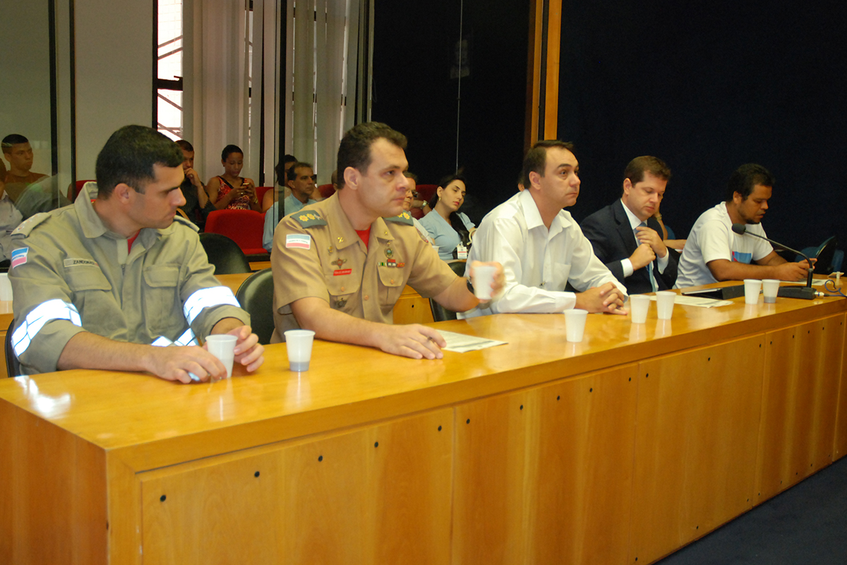 several men sitting at the end of a desk in front of a crowd