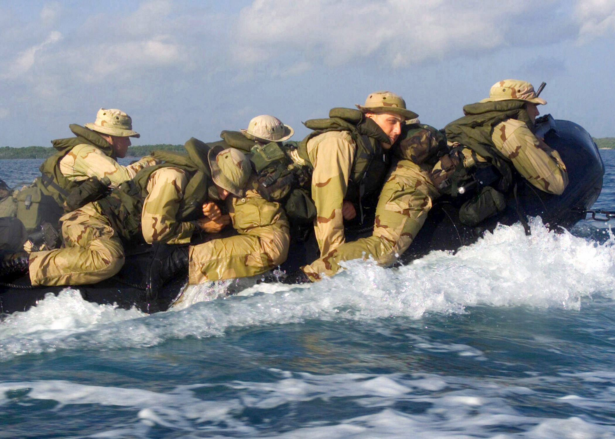 a group of soldiers is on an inflatable raft in the water