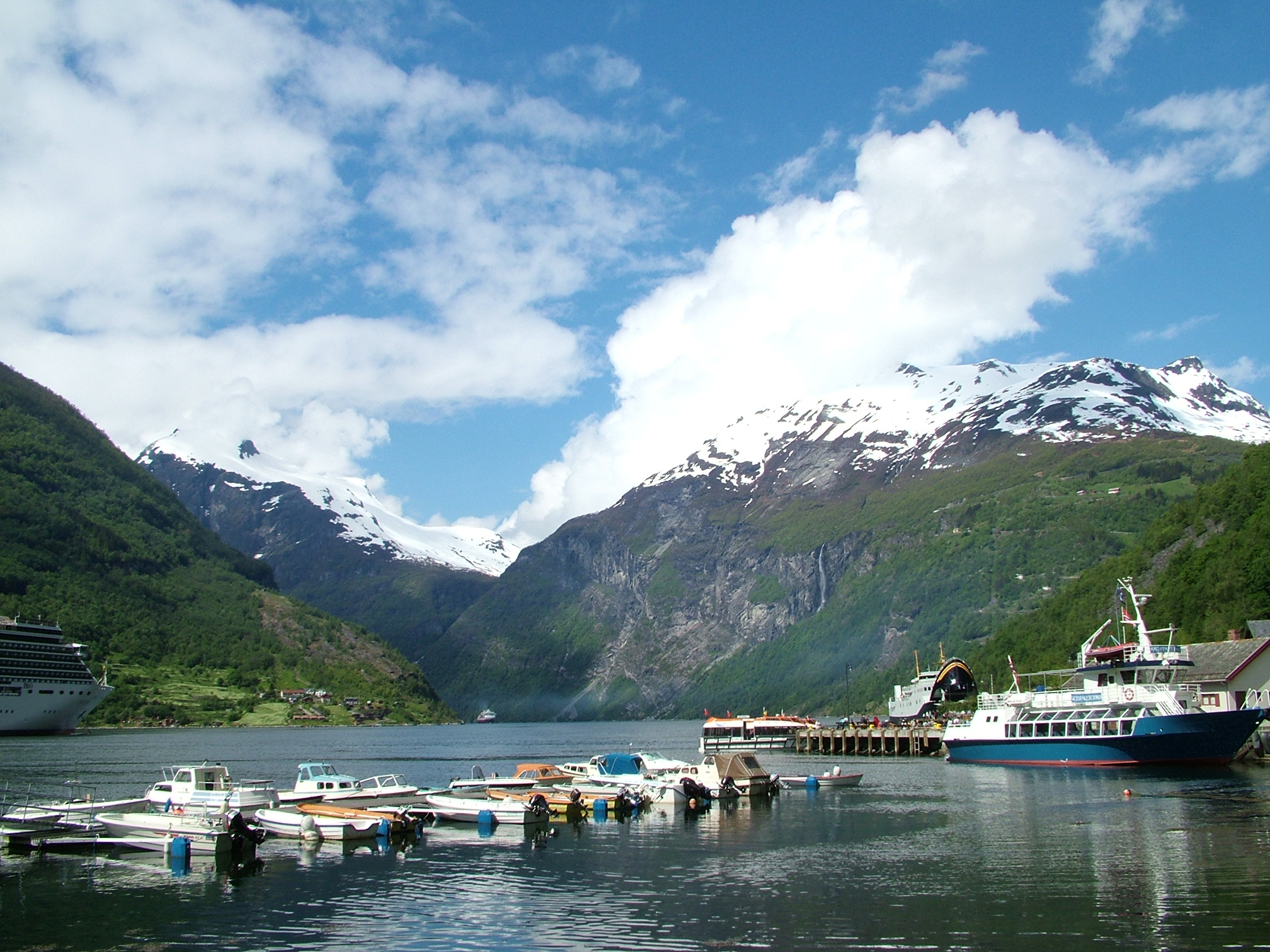 a boat docked on the waters near some mountains