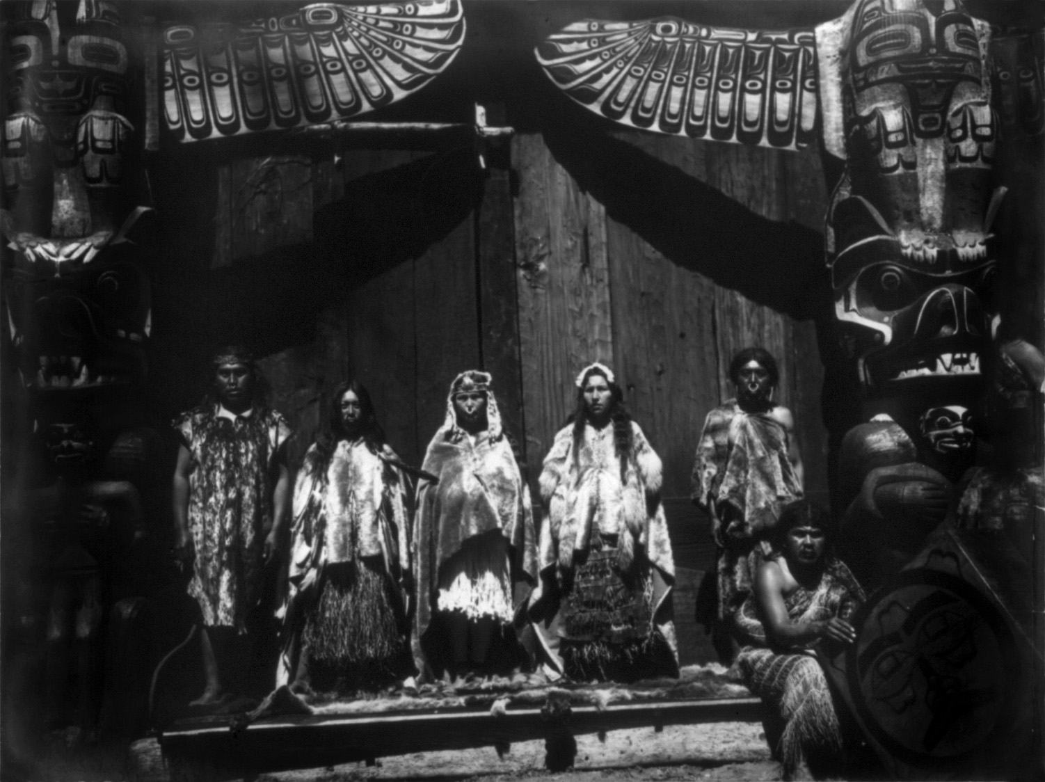 five masked men stand in front of a door