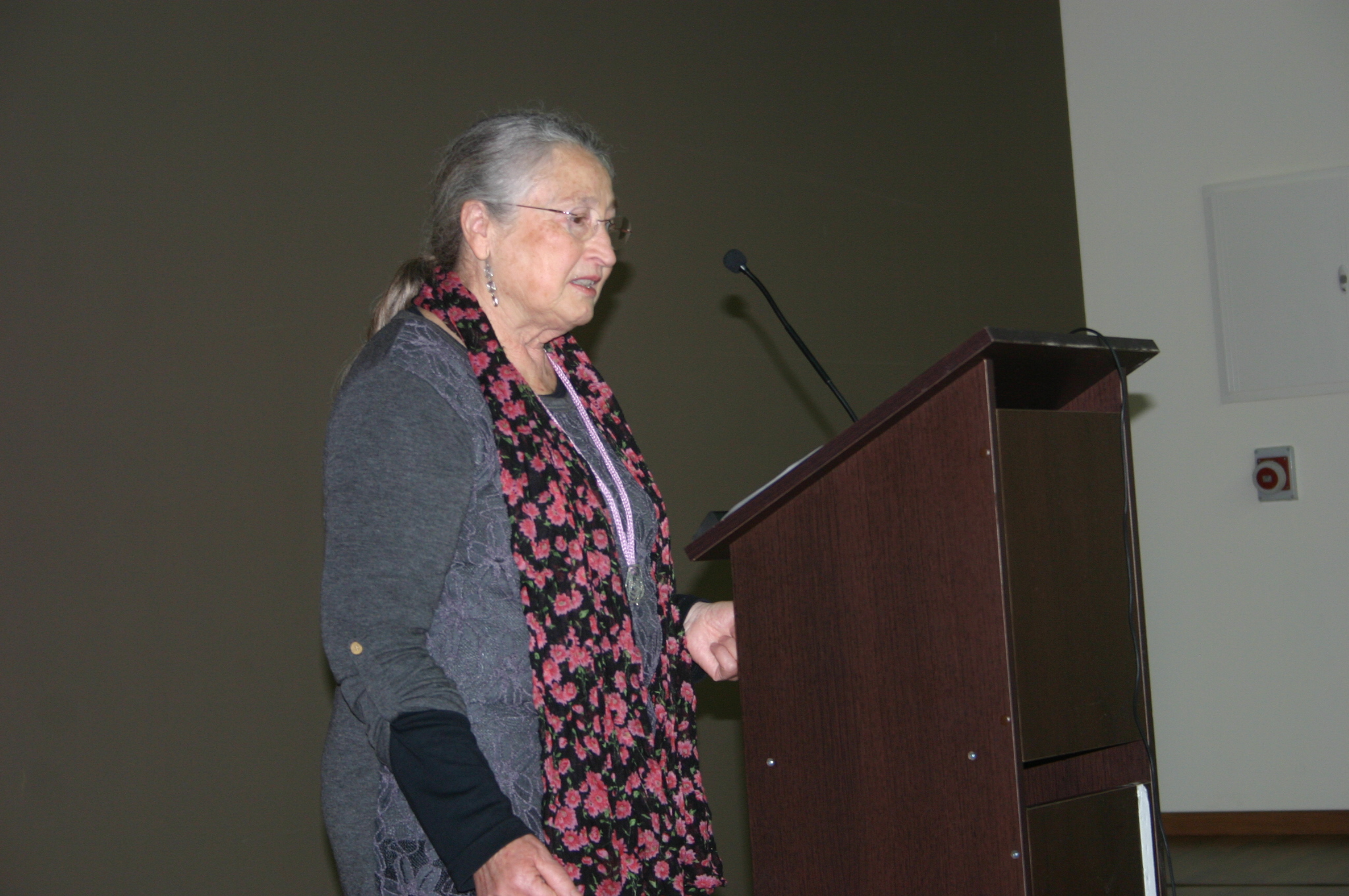 a person standing at a podium wearing a scarf
