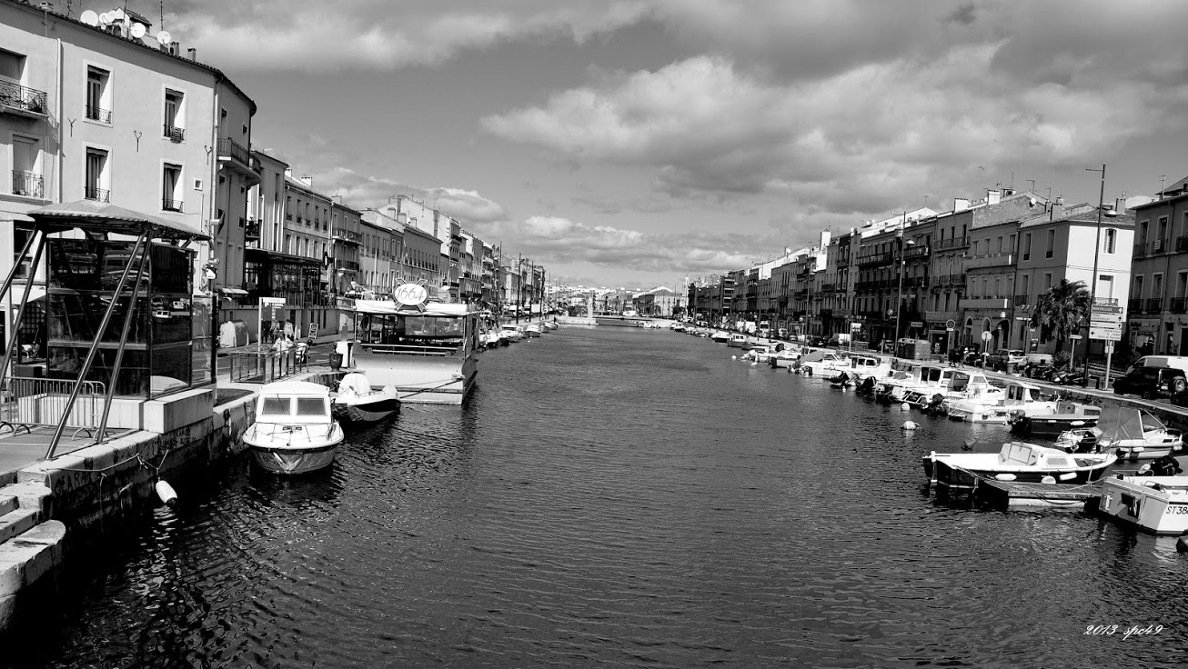 a black and white image of a canal with boats in the water
