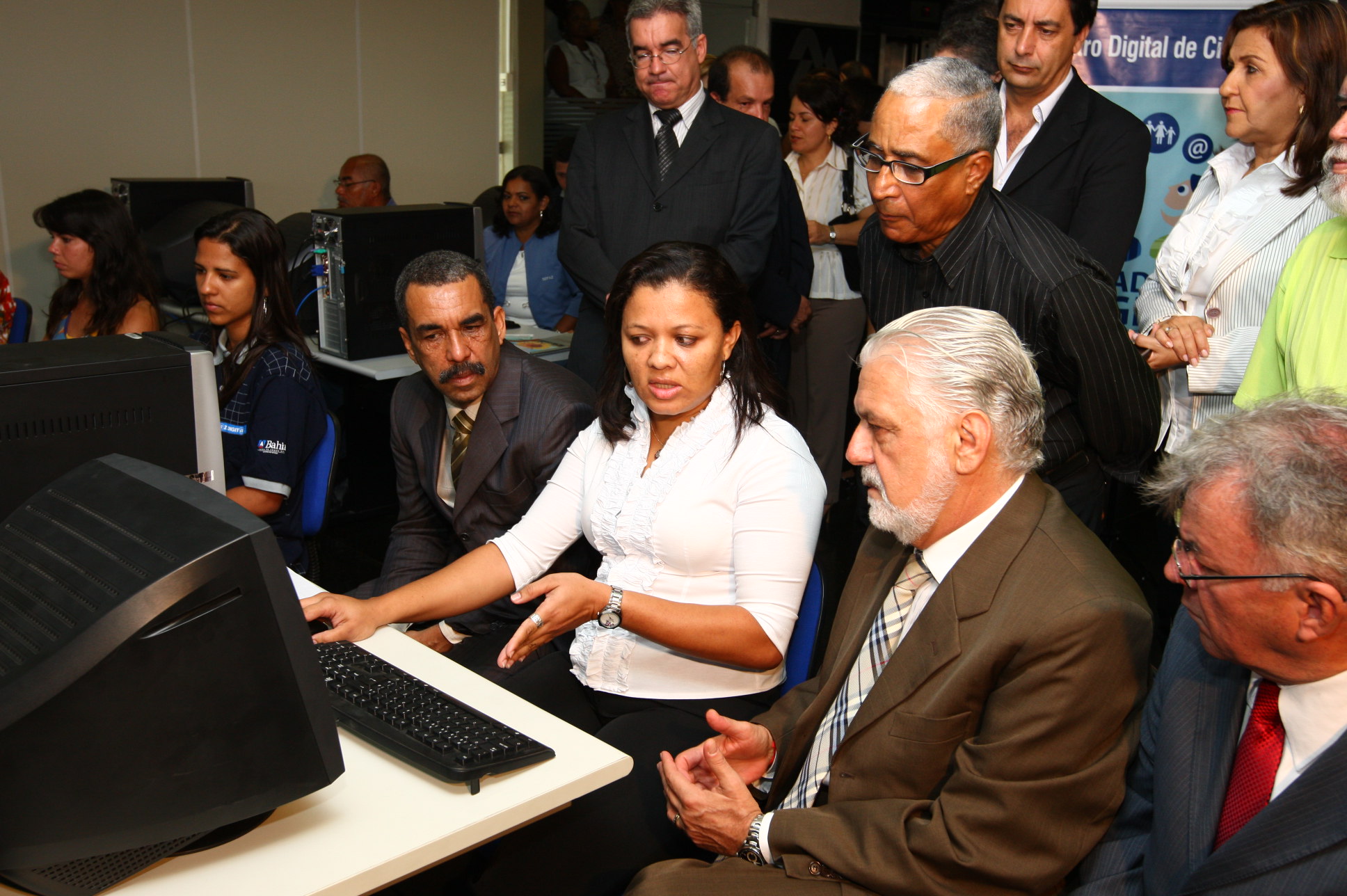 a group of people in front of computers and an older person pointing