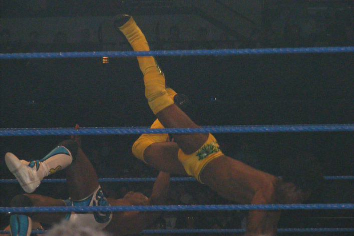a wrestler flips up in the air above the crowd