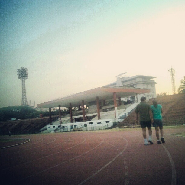 two men are running on a basketball court in front of a stadium
