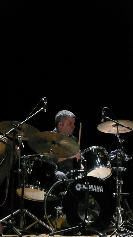 the man is playing the drums and sitting in a black stage