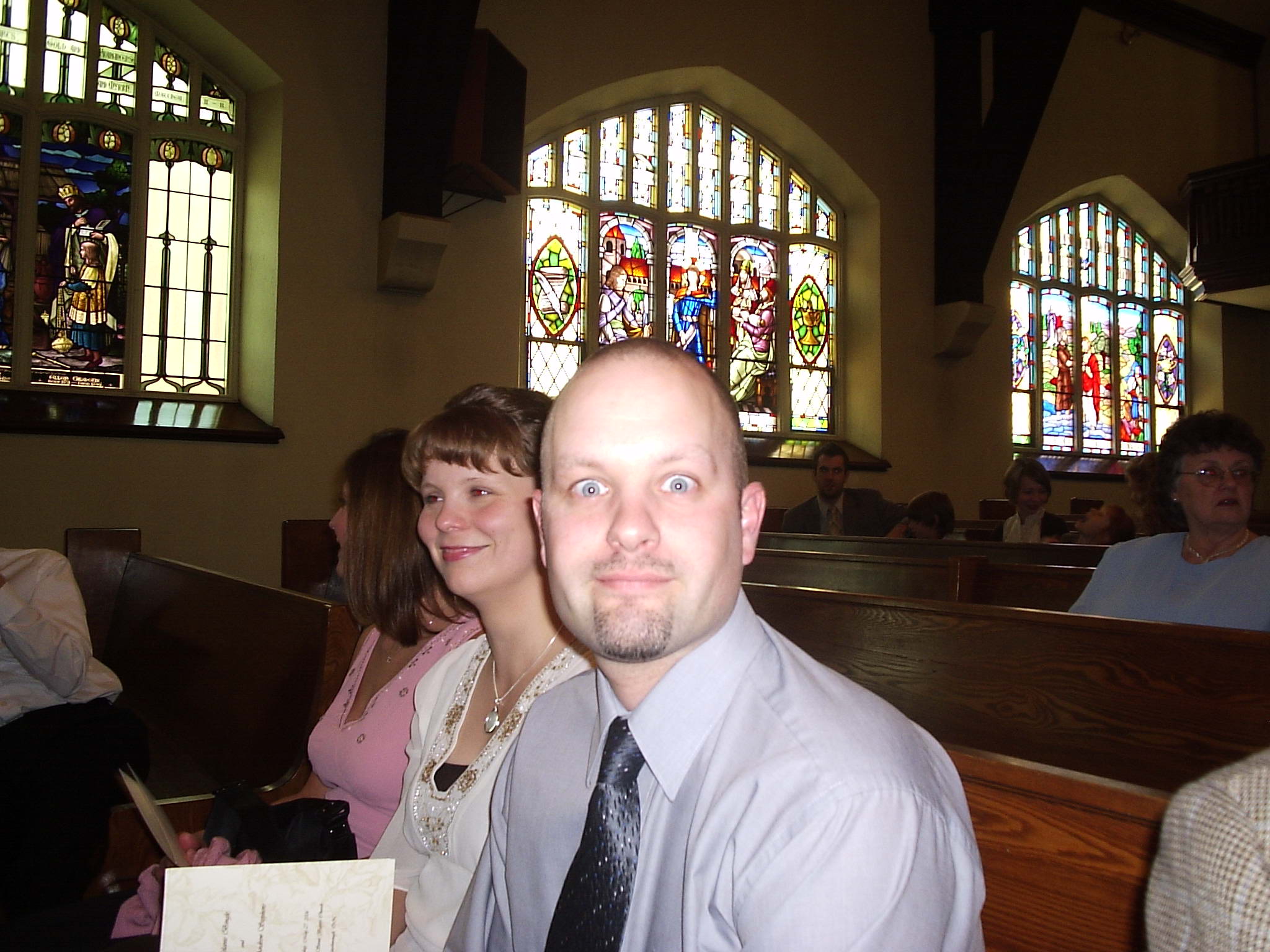 people sitting in pews in a church with stained glass windows