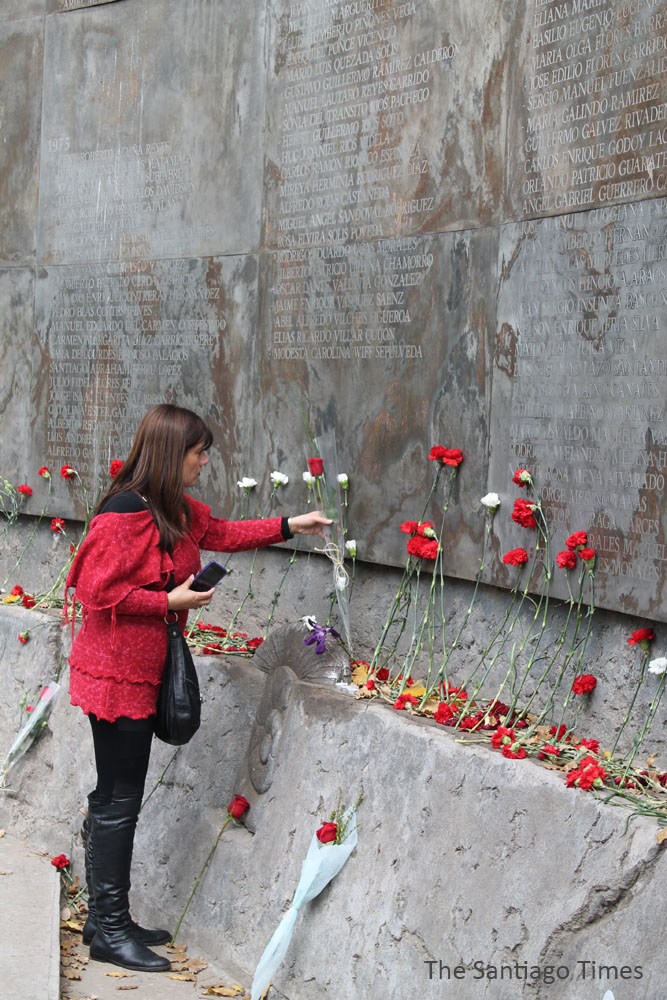 a woman standing next to flowers at the base of the vietnam war memorial