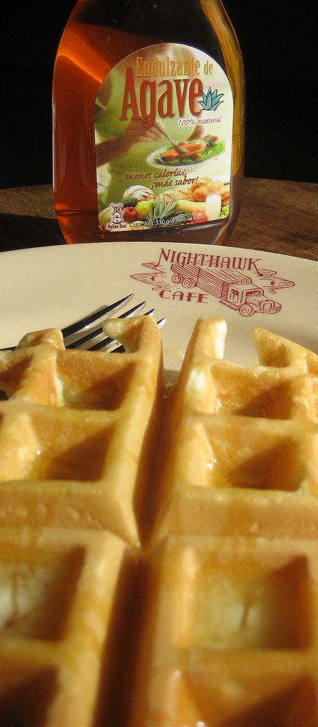 a waffle on a plate with syrup in the background