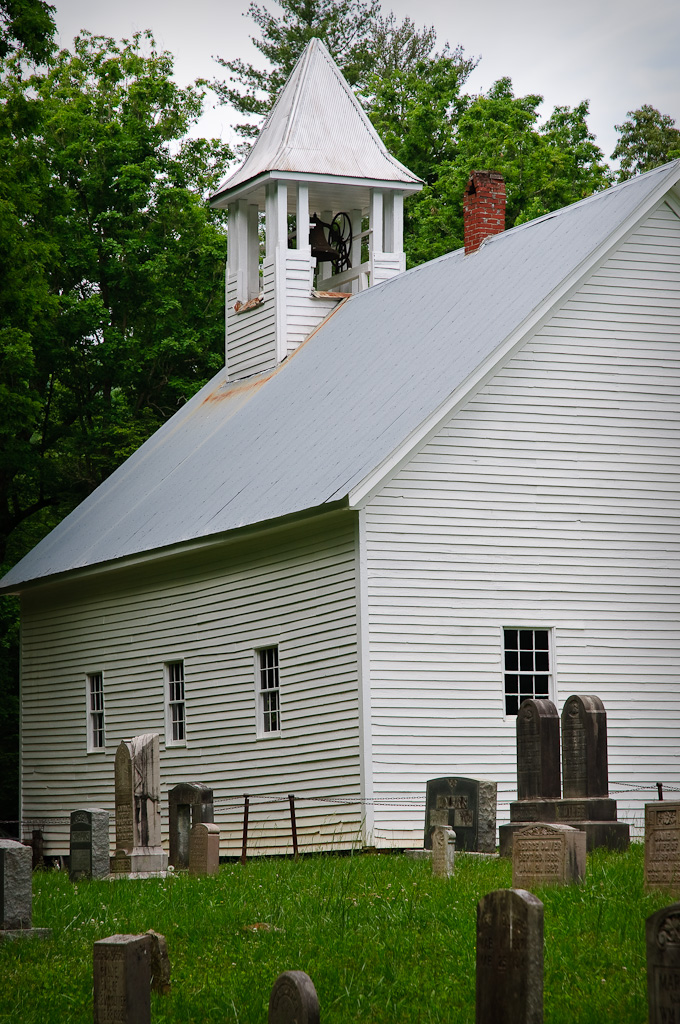 a white church in a cemetery near trees