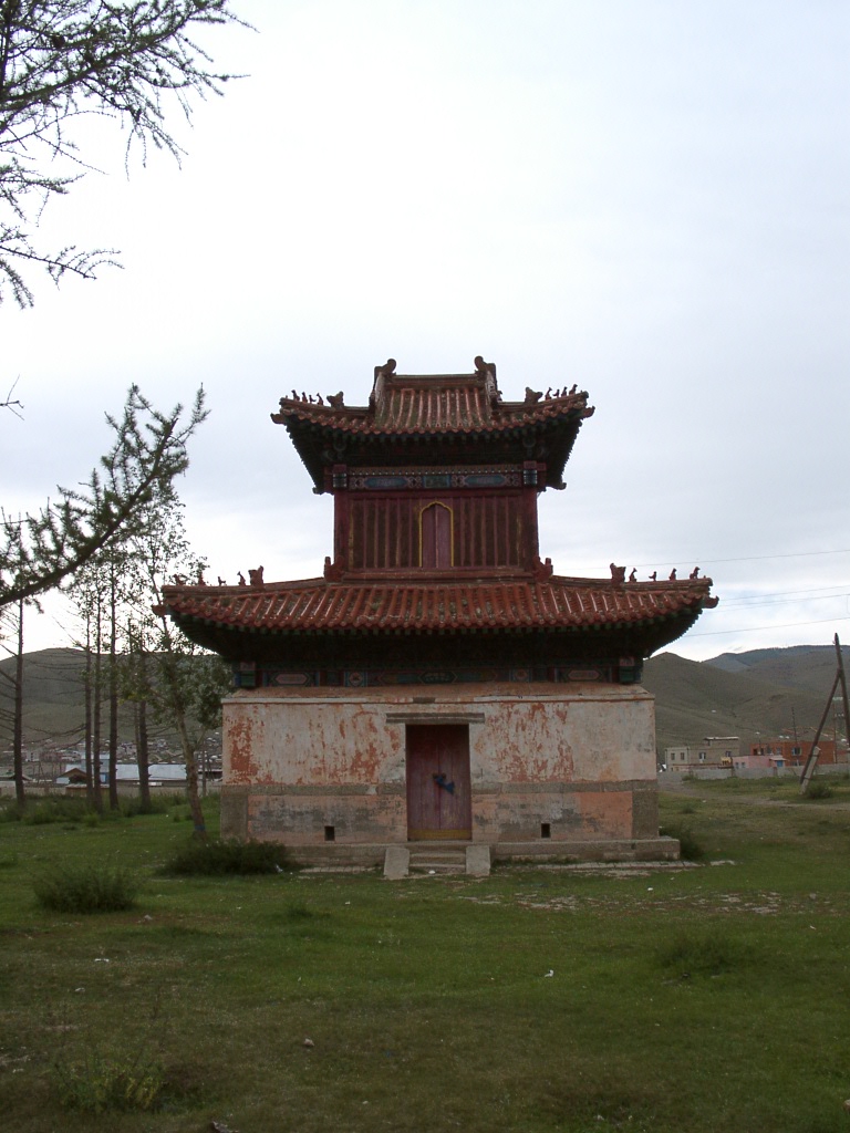 a small building with a big roof in a field