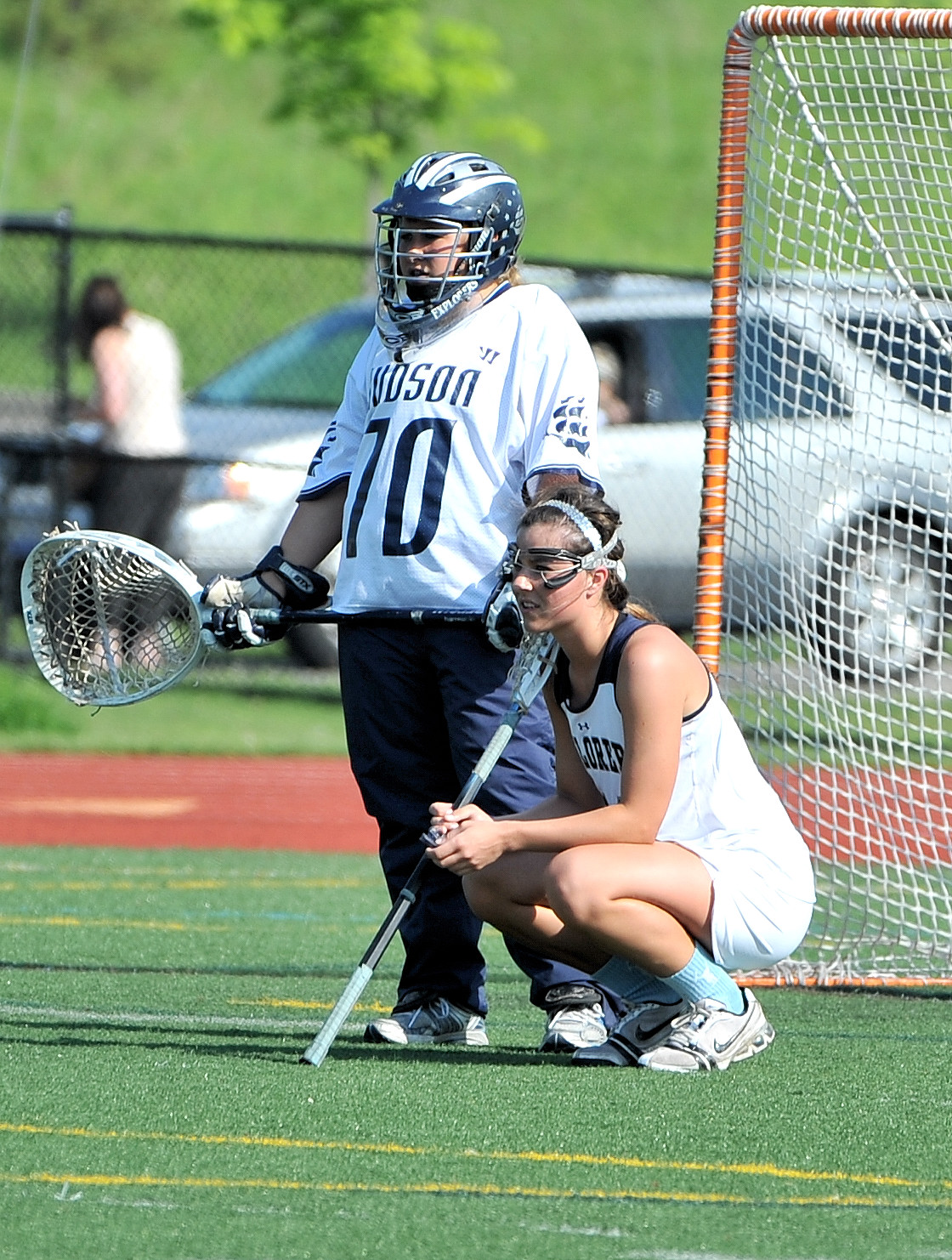 a lacrosse player holding the ball and a referee in the background