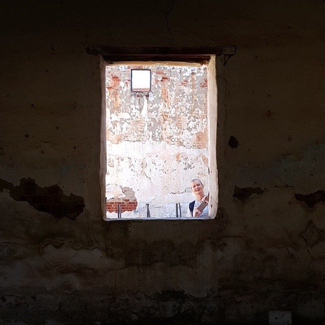 a window in the wall of a large building with one woman sitting at a table