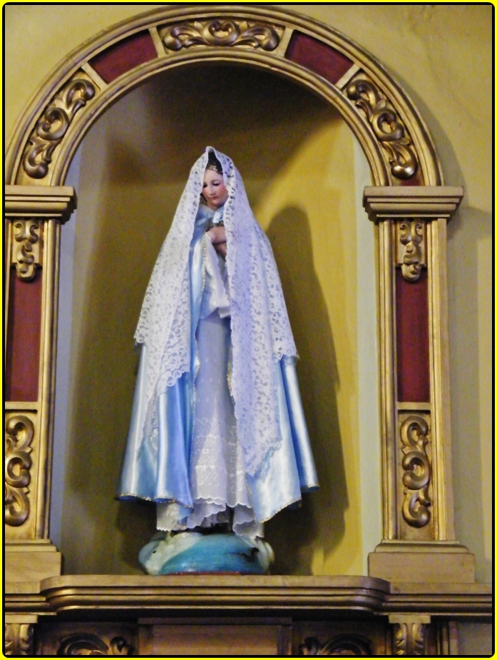 statue of a woman dressed as the virgin mary in a frame