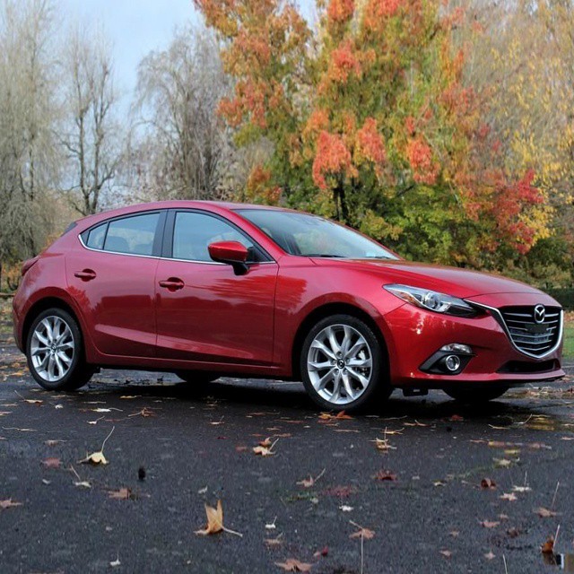a red mazda vehicle parked on the side of the road