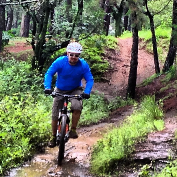 a man riding his bike through a small stream in the woods