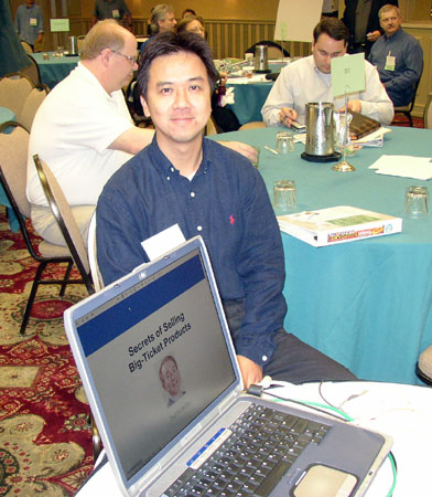 man sitting behind a laptop at a conference