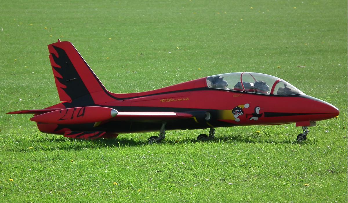 a red plane sitting in the grass of a field