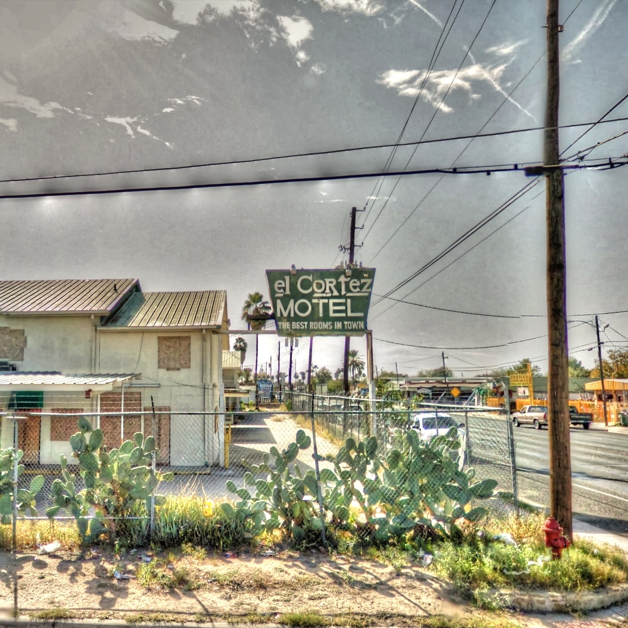 the motel sign has a lot of plants in front of it