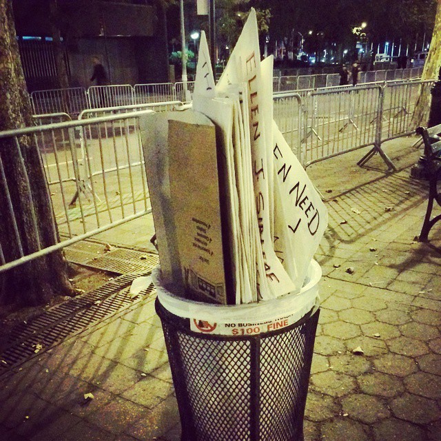 a trash can holding magazines on top of it
