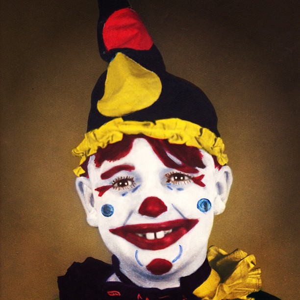 a creepy clown with blue eyes in yellow