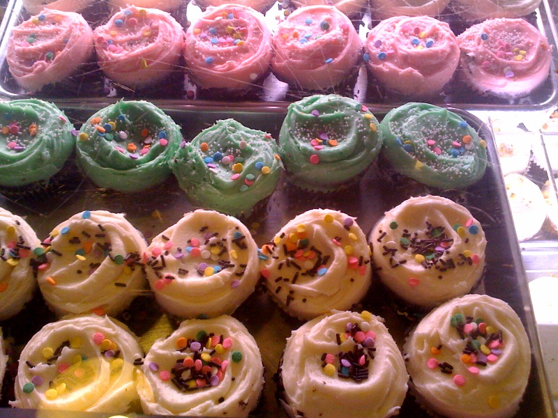 assorted colored and sprinkled donuts in a case