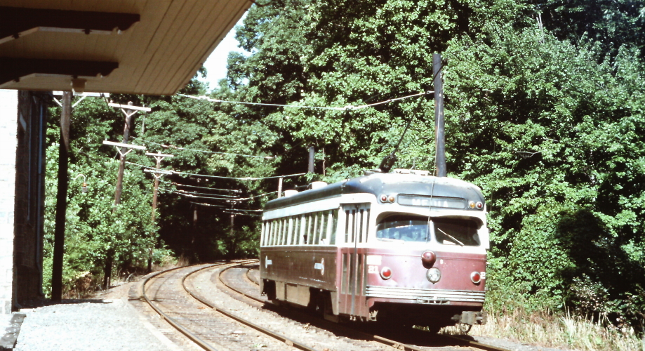 a trolley is traveling down the tracks in a forest